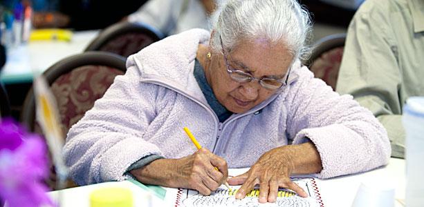 Una mujer mayor escribiendo.